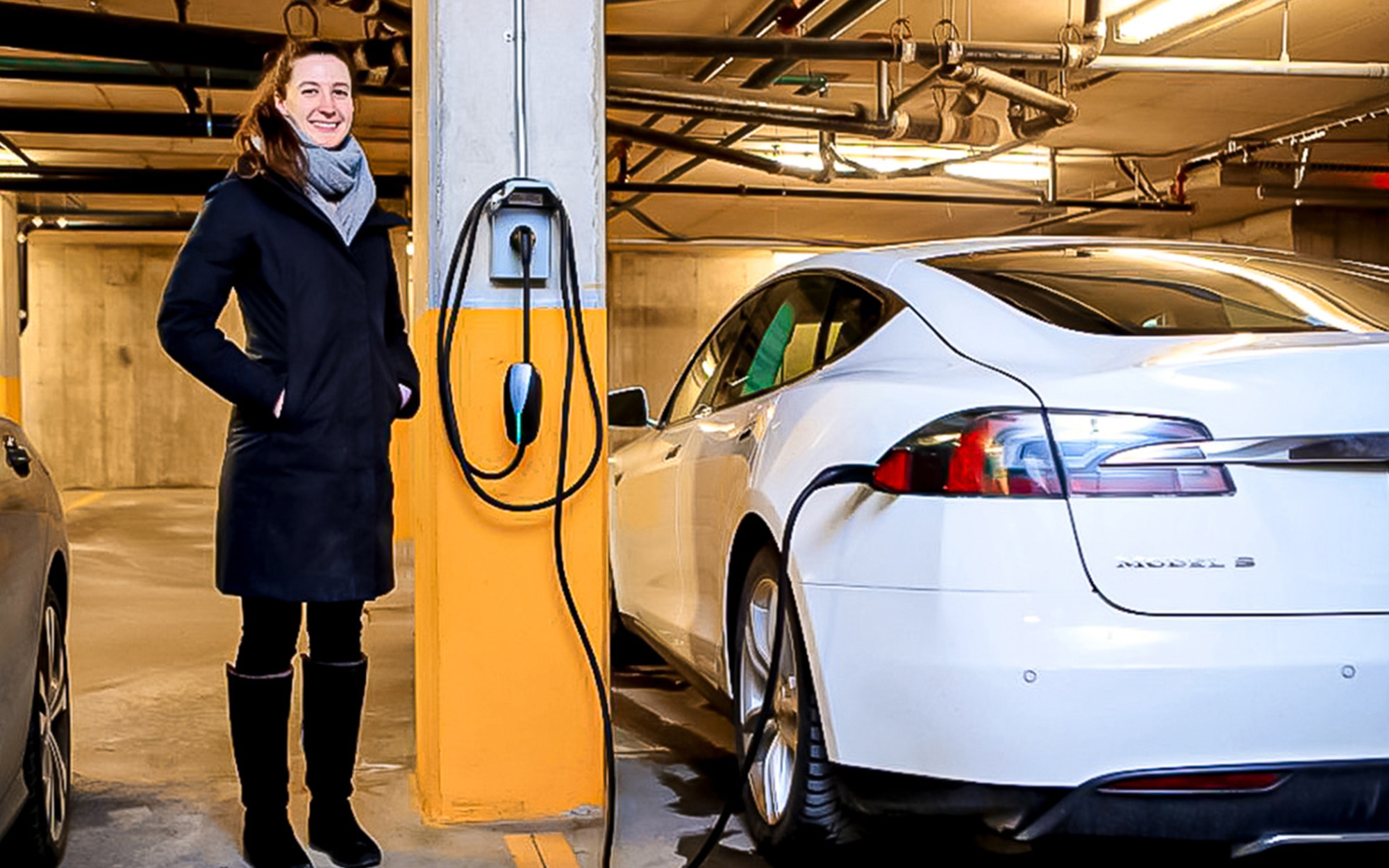 Side view of smiling woman standing next to a Tesla
